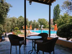 een patio met een tafel en stoelen en een zwembad bij Nakellis Studios in Petra