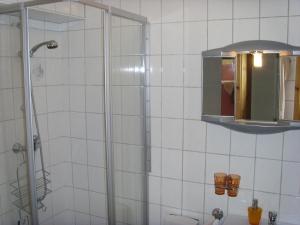 une salle de bain carrelée blanche avec une douche et un miroir dans l'établissement Ferienwohnung Ina, à Rust 15 autres photos