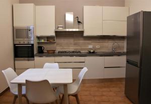 a kitchen with white cabinets and a white table and chairs at Anna's Apartment, the Heart of Bologna. in Bologna