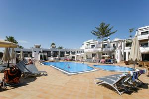 a large swimming pool with lounge chairs and umbrellas at Club Oceano in Puerto del Carmen +36 photos