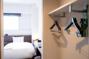 a bedroom with a bed and a door with hangers at Hotel Wing International Asahikawa Ekimae in Asahikawa