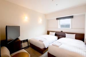 um quarto de hotel com duas camas e uma televisão de ecrã plano em Hotel Wing International Asahikawa Ekimae em Asahikawa
