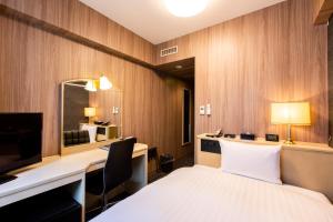 a hotel room with a bed and a desk and a mirror at Hotel Wing International Asahikawa Ekimae in Asahikawa