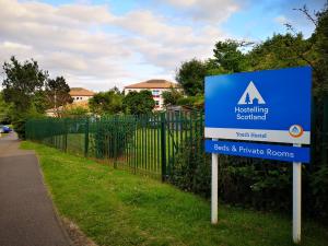 Un cartel que anuncia una escuela residencial junto a una valla. en Inverness Youth Hostel, en Inverness