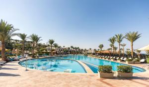a pool at a resort with palm trees and chairs at Sunrise Montemare Resort -Grand Select in Sharm El Sheikh