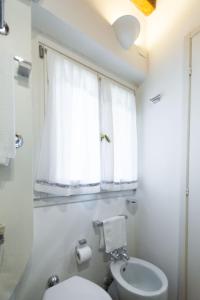 biała łazienka z toaletą i oknem w obiekcie TICINESE 59 APARTMENT w Mediolanie