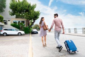a man and a woman walking with a suitcase at Hotel Miramare - Adults Only in Trieste