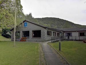 a stone building with a grass yard in front of it at Aviemore Youth Hostel in Aviemore