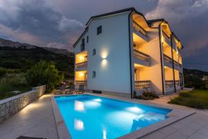 a villa with a swimming pool in front of a building at Bed & Breakfast Došen III in Baška
