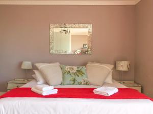 a bedroom with a bed with a red blanket and a mirror at Bluebottle Guesthouse in Muizenberg