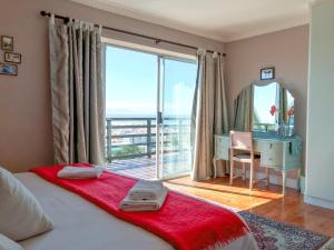 a bedroom with a bed and a desk and a large window at Bluebottle Guesthouse in Muizenberg