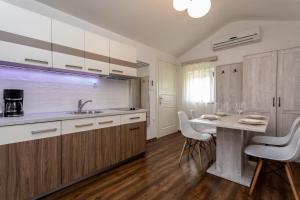 a kitchen with white cabinets and a table with chairs at Bed & Breakfast Došen V in Baška