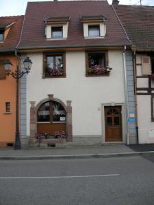 um edifício branco com caixas de flores nas janelas em Le gîte de Gab em Eguisheim