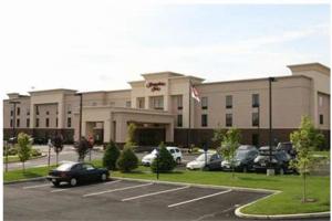 Hampton Inn North Brunswick NJ في نورث برونزويك: مبنى كبير به سيارات تقف في موقف للسيارات