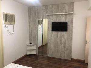 Apto aconchegante 100m Shopping Beiramar في فلوريانوبوليس: غرفة بها جدار مع تلفزيون بشاشة مسطحة