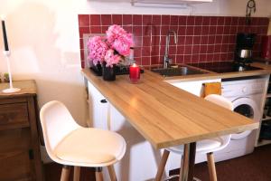 una cocina con encimera de madera con sillas blancas y flores rosas en Mon Mounier : Studio cosy au pied des pistes / Vue de rêve !, en Beuil