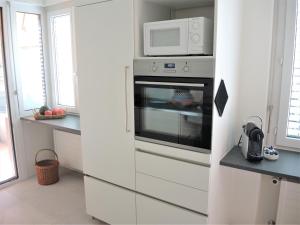 a white kitchen with a microwave above a oven at Bellavista in Locarno