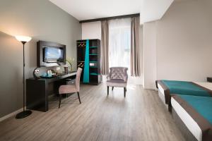 a bedroom with a bed and a desk and a television at Arcadia Hotel Budapest in Budapest