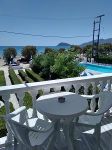 een witte tafel en stoelen op een balkon met een zwembad bij Villa Doris in Laganas
