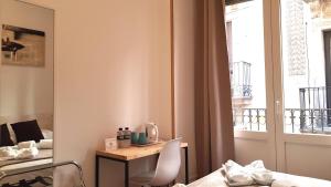 a room with a desk and a bed and a window at Hostal la Palmera in Barcelona