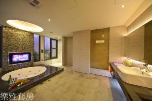 a bathroom with a tub and a sink and a tv at Doule Motel in Taichung +77 photos