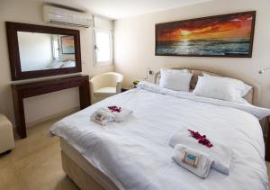 a bedroom with a white bed with two towels and a mirror at Ha-aliya Sea View in Nahariyya
