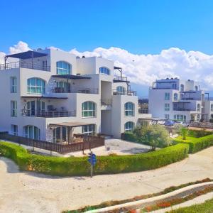 ein großes weißes Apartmenthaus am Strand in der Unterkunft Aphrodite Apartments North Cyprus in Ghaziveran