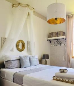 - une chambre avec un lit doté de draps blancs et d'un miroir dans l'établissement La Maison Au Bois Dormant, à Barraux