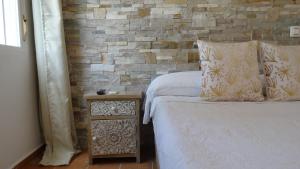 a bedroom with two beds and a brick wall at Hostal Residencial La Paloma in Calpe