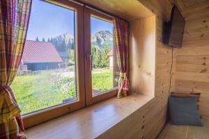 una ventana en una cabaña de madera con vistas a las montañas en ŠIBALIĆ APARTMANI, en Žabljak