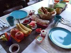 a table with fruit and bread and plates on it at La Maison Du Marchand in Peyrat-le-Château