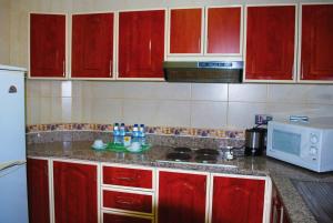 a kitchen with red cabinets and a white microwave at Green Mubazzarah Chalets in Al Ain