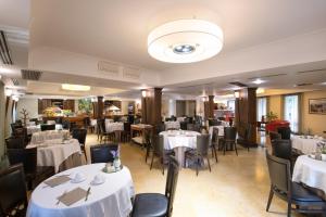 a dining room with white tables and chairs at Artemis Hotel in Cefalù