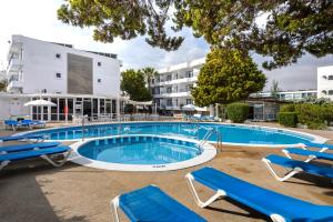 - une piscine avec des chaises longues bleues en face d'un bâtiment dans l'établissement Hotel Vibra Isola - Adults only, à Playa d'en Bossa
