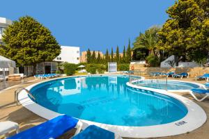 una gran piscina con sillas azules y árboles en Hotel Vibra Isola - Adults only, en Playa d'en Bossa