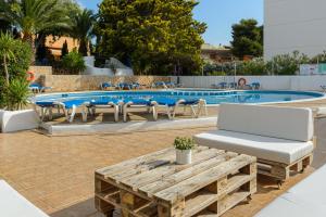 einen Pool mit Liegestühlen, einem Tisch und einer Bank in der Unterkunft Hotel Vibra Isola - Adults only in Playa d'en Bossa