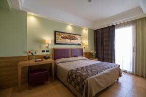 a hotel room with a bed and a table and a window at Artemis Hotel in Cefalù