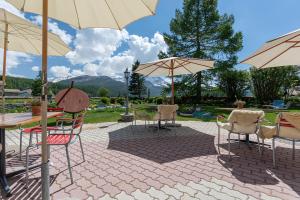 een patio met stoelen, tafels en parasols bij Hotel Chesa Randolina in Sils Maria