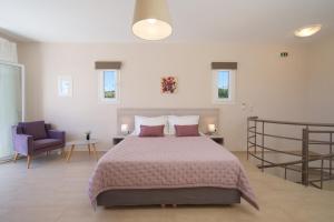 a bedroom with a large bed and a purple chair at Rose Maisonette in Kefallonia