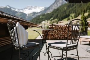 two chairs and a table on a balcony with mountains at Wildstrubel Lodge in Adelboden