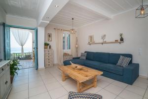 Anemos Beach House في اليكاناس: غرفة معيشة مع أريكة زرقاء وطاولة