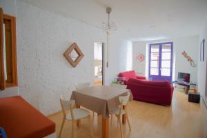 sala de estar con mesa y sofá rojo en La Lleona Apartment, en Girona