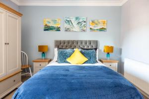 um quarto com uma cama azul com três pinturas na parede em BlueNess, City Centre Luxury Apartment em Inverness