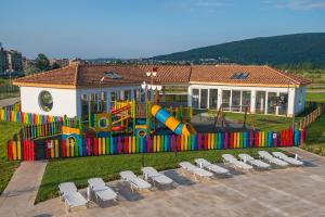 a playground with a slide and chairs in front of a building at Sunrise Blue Magic Resort - All Inclusive in Obzor