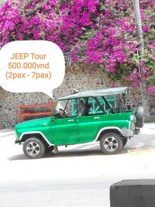 a green jeep parked on a street with purple flowers at The House 17/1 in Mui Ne