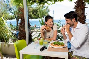 a man and woman sitting at a table eating food at Hotel Miramare - Adults Only in Trieste
