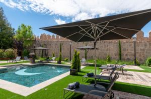 un patio trasero con piscina y sombrilla en La Casa del Presidente, en Ávila