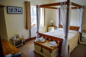 a bedroom with a canopy bed and a window at Abbey Grange Hotel in Llangollen