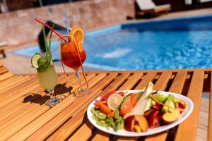 un piatto di cibo e due bevande su un tavolo accanto alla piscina di Prezident Hotel a Novi Sad Altre 37 foto