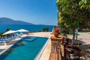 a swimming pool with chairs and the ocean in the background at Hotel "SAN SAENA " in Vlorë